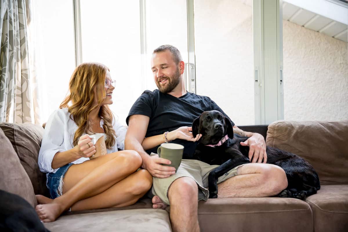 Female and male sitting on a couch holding mugs