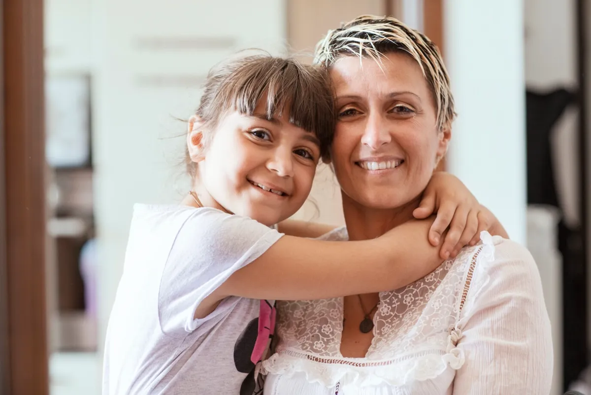 woman and child in white shirts smiling at camera